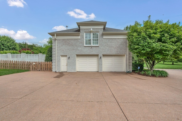 view of home's exterior featuring concrete driveway, fence, an attached garage, and brick siding