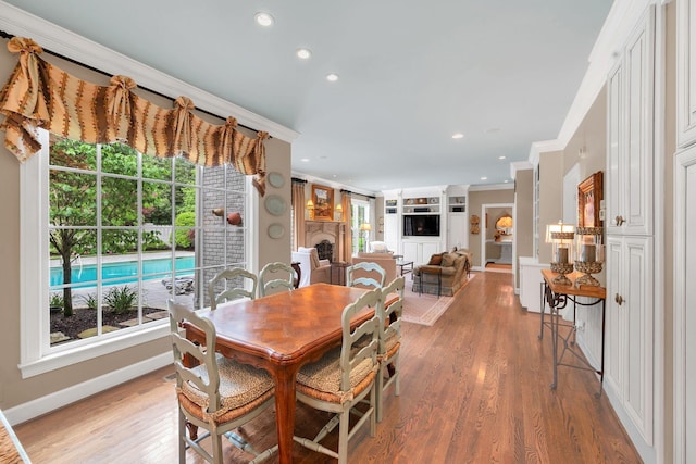 dining area with ornamental molding, recessed lighting, light wood finished floors, a fireplace, and baseboards