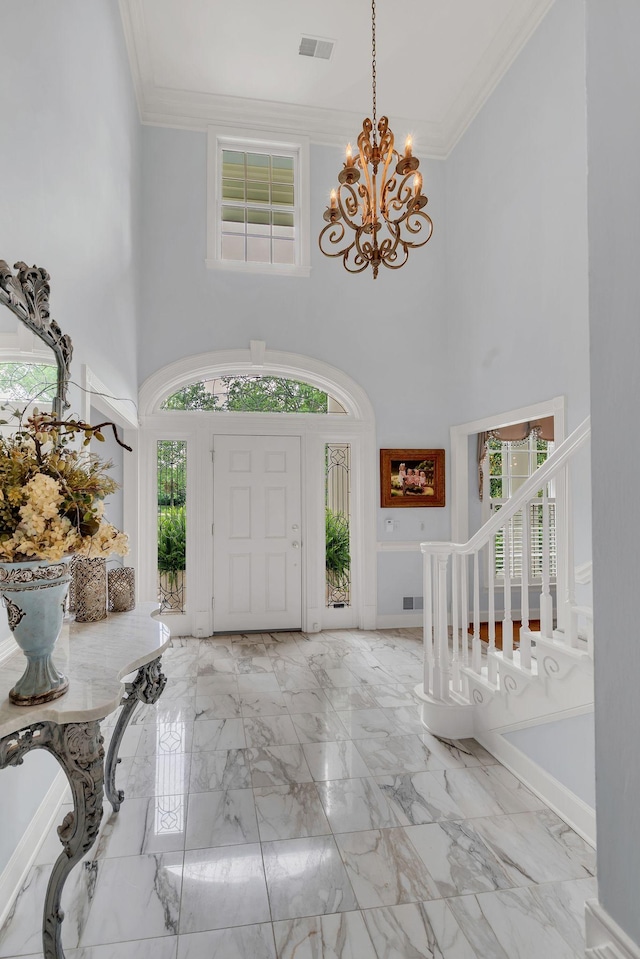 entryway with a chandelier, a towering ceiling, crown molding, marble finish floors, and baseboards