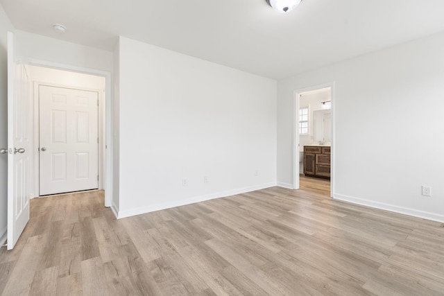 spare room with light wood-type flooring, baseboards, and a smoke detector