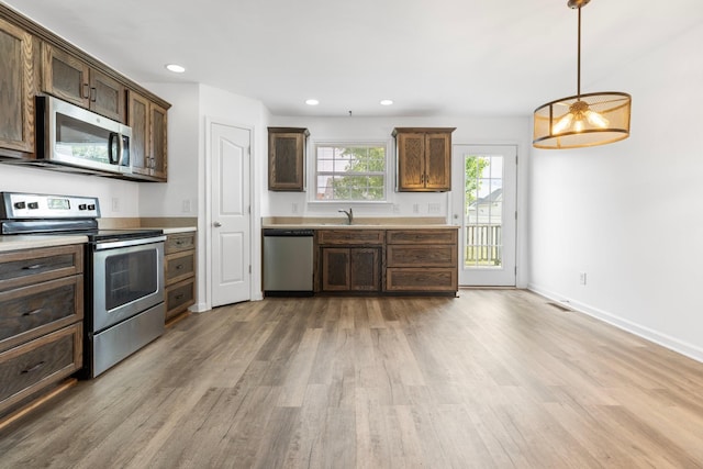kitchen featuring stainless steel appliances, light wood-style flooring, a sink, light countertops, and recessed lighting