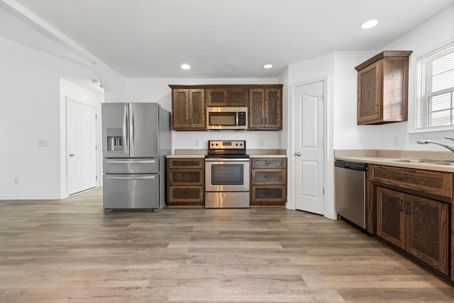 kitchen featuring appliances with stainless steel finishes, a sink, light wood-style flooring, recessed lighting, and light countertops