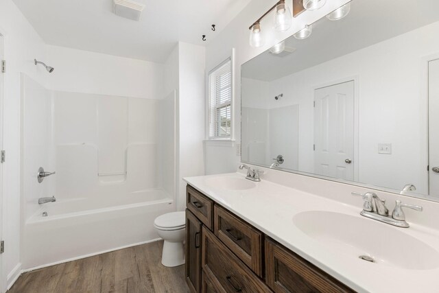 full bath featuring wood finished floors, toilet, shower / washtub combination, and double vanity