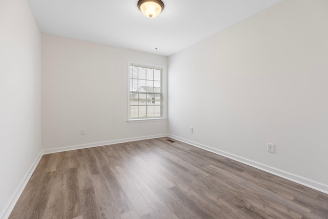 empty room featuring wood finished floors and baseboards
