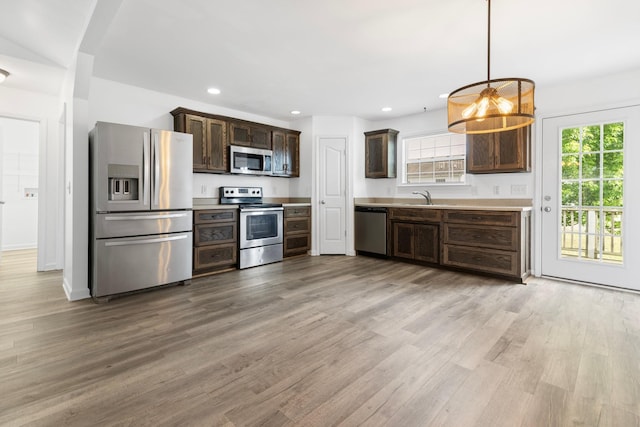 kitchen with stainless steel appliances, dark brown cabinetry, light wood-style flooring, a sink, and recessed lighting