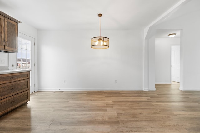 unfurnished dining area with light wood-type flooring and baseboards