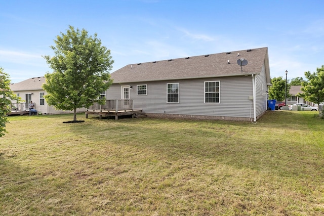 back of property featuring a deck, a yard, and a shingled roof