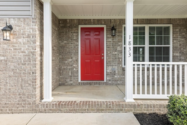 property entrance featuring covered porch and brick siding