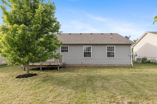 rear view of property with a lawn, a deck, and a shingled roof