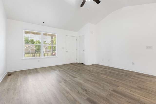 spare room with vaulted ceiling, ceiling fan, wood finished floors, and baseboards