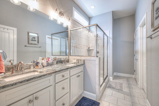 full bath featuring a stall shower, double vanity, and baseboards