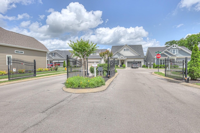 view of asphalt street with a residential view, traffic signs, and a gated entry