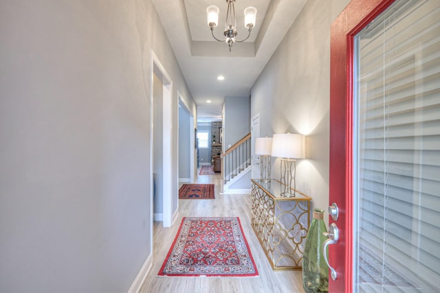 hall featuring wood finished floors, stairs, a chandelier, and baseboards