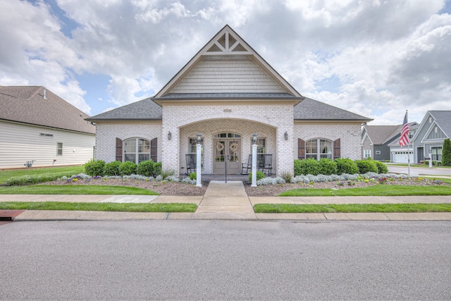 french country inspired facade featuring french doors, brick siding, and roof with shingles