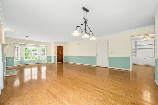 spare room with crown molding, ceiling fan, light wood-type flooring, built in shelves, and baseboards