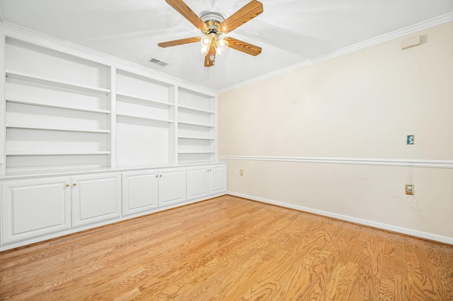unfurnished room featuring light wood-type flooring, baseboards, crown molding, a ceiling fan, and built in shelves