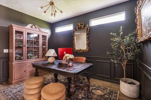 office area with a decorative wall, a chandelier, wood finished floors, healthy amount of natural light, and wainscoting