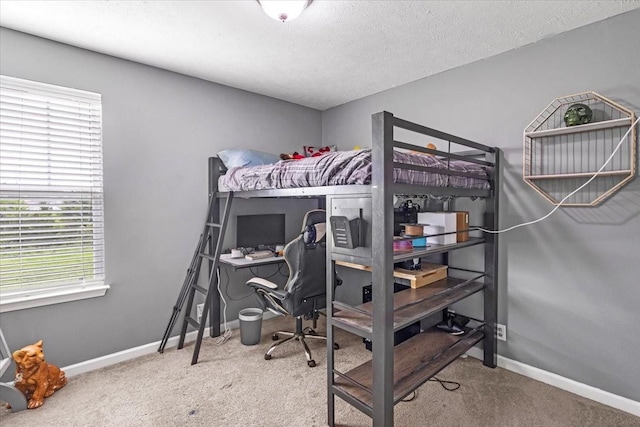 carpeted bedroom featuring an office area, baseboards, and a textured ceiling