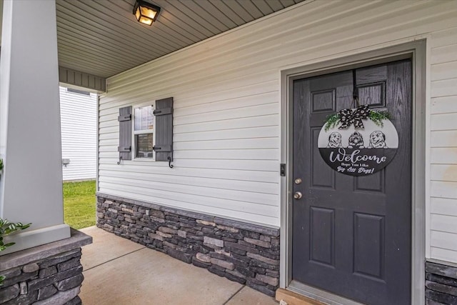 doorway to property featuring a porch and stone siding