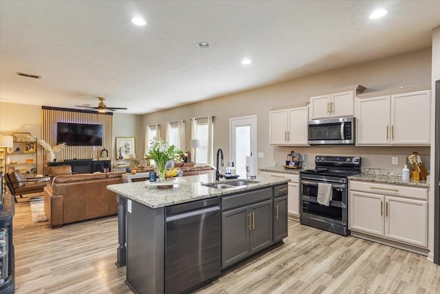 kitchen featuring appliances with stainless steel finishes, a sink, white cabinets, light wood-type flooring, and recessed lighting