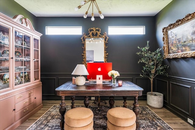 dining space featuring plenty of natural light, wood finished floors, wainscoting, a decorative wall, and an office area
