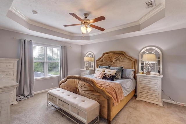 bedroom with a tray ceiling, ornamental molding, light carpet, and baseboards