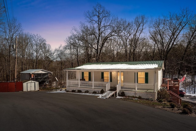 6966 Park Dr, Lyles, TN 37098 - view of front of home with covered porch, a storage unit, an outbuilding, and metal roof