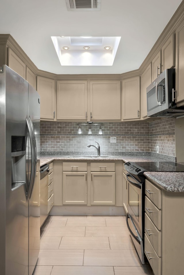 kitchen featuring stainless steel appliances, a sink, backsplash, and light stone counters