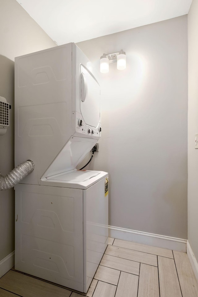 laundry room featuring stacked washer and clothes dryer and baseboards