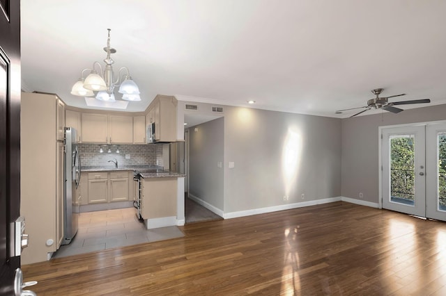 kitchen featuring open floor plan, appliances with stainless steel finishes, a chandelier, baseboards, and crown molding