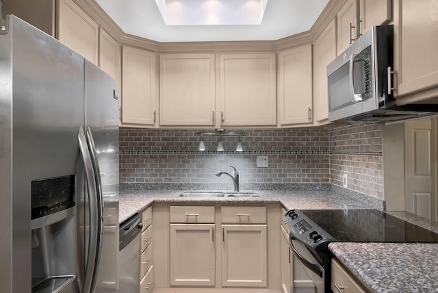kitchen with appliances with stainless steel finishes, a sink, decorative backsplash, and light stone counters