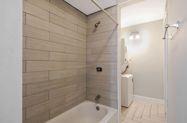 bathroom with shower / bath combination, baseboards, and washer / dryer
