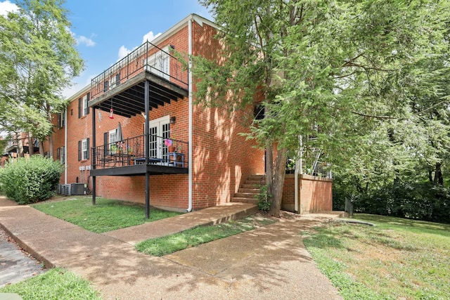 view of side of home featuring a balcony, brick siding, and central air condition unit
