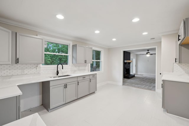 909 Plateau Pkwy, Nashville, TN 37205 - kitchen featuring gray cabinetry, a sink, ornamental molding, decorative backsplash, and a brick fireplace