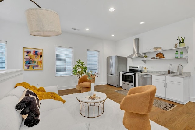 1056E 2nd Ave S, Nashville, TN 37210 - kitchen featuring appliances with stainless steel finishes, a sink, range hood, open shelves, and light wood finished floors