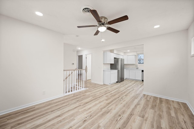 unfurnished living room featuring light wood finished floors, a ceiling fan, a sink, recessed lighting, and baseboards