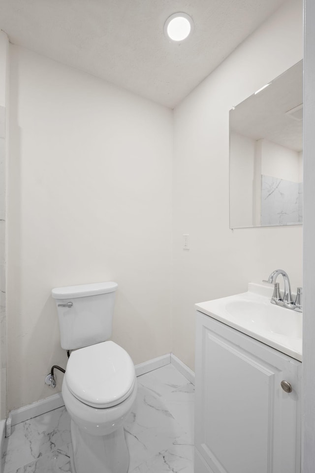 bathroom featuring marble look tile flooring, baseboards, and vanity