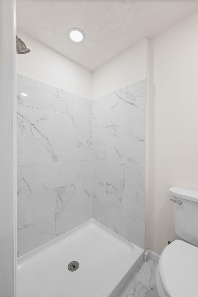 full bath with marble finish floors, a shower stall, toilet, and baseboards