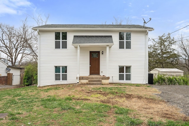 split foyer home featuring a front lawn and roof with shingles