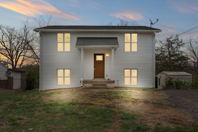 view of front of house with a front yard, a storage shed, and an outbuilding