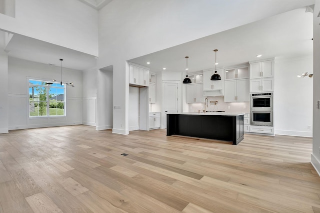 1018 Keeneland Dr, Gallatin, TN 37066 - kitchen featuring stainless steel double oven, light wood-style flooring, white cabinetry, light countertops, and baseboards