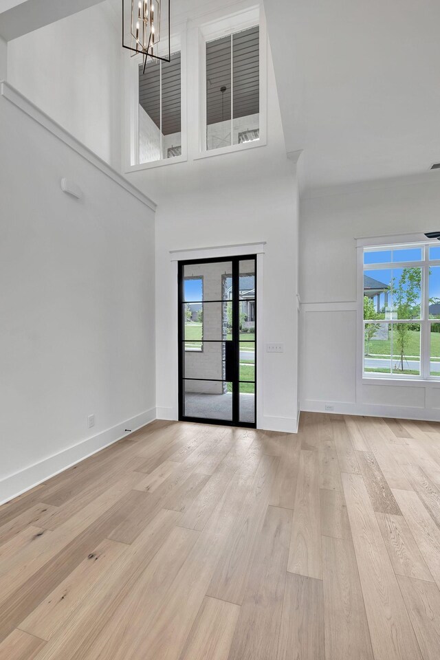1018 Keeneland Dr, Gallatin, TN 37066 - unfurnished living room featuring a chandelier, light wood-style flooring, baseboards, and a towering ceiling