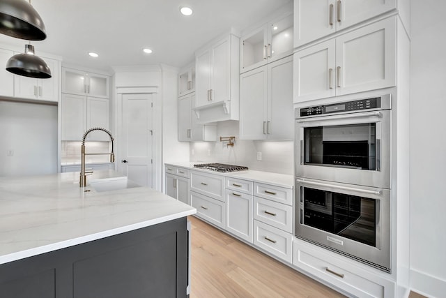 1018 Keeneland Dr, Gallatin, TN 37066 - kitchen featuring appliances with stainless steel finishes, a sink, glass insert cabinets, light stone counters, and recessed lighting