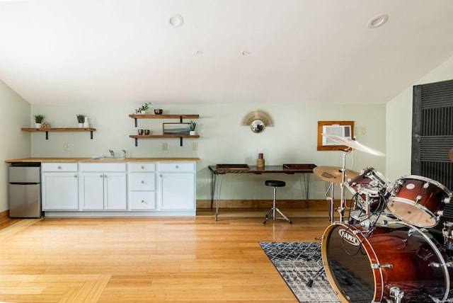 misc room with baseboards, light wood finished floors, a sink, and recessed lighting