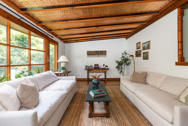 living room featuring wood finished floors, baseboards, and beamed ceiling