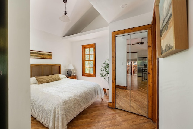 bedroom featuring high end refrigerator, wood finished floors, and lofted ceiling
