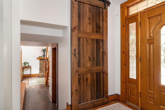 entryway with dark wood finished floors, baseboards, and a barn door