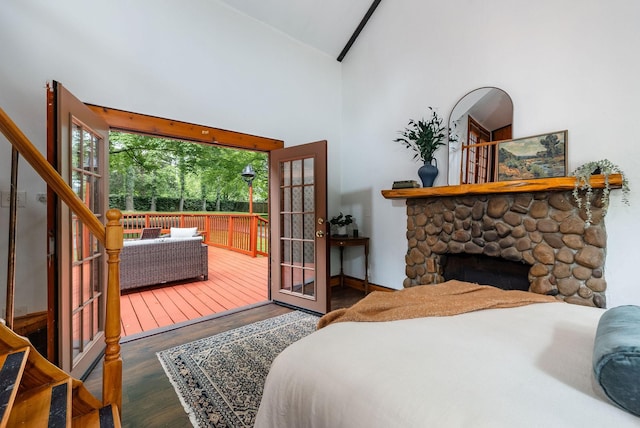 bedroom featuring high vaulted ceiling, wood finished floors, access to outside, a fireplace, and baseboards