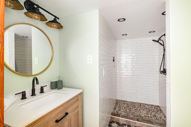 bathroom with a tile shower, recessed lighting, and vanity