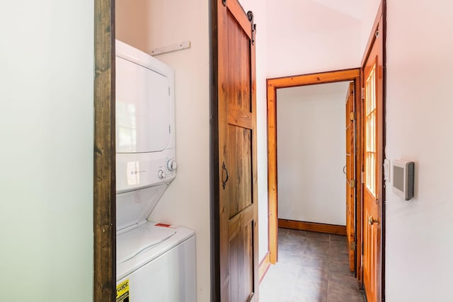 laundry room with stacked washer and clothes dryer and a barn door